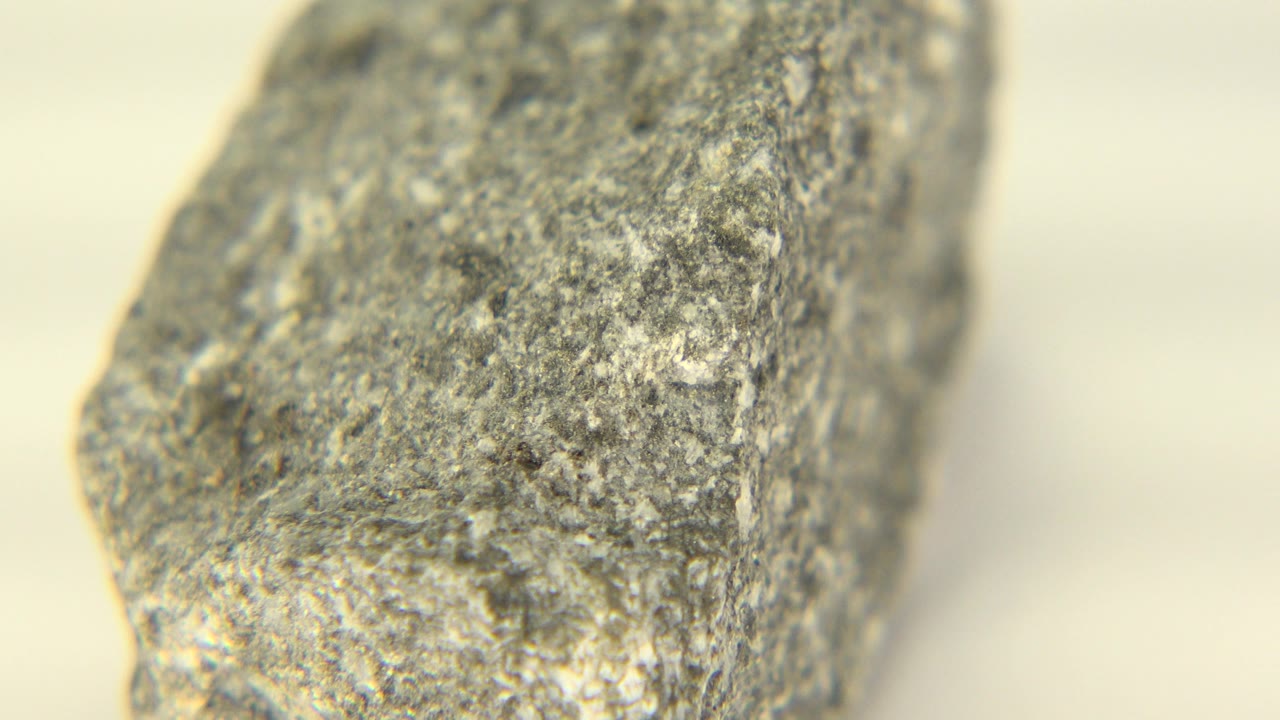 At 0:00, a gray speckled stone or marble fragment fills the left side of a close-up frame in Westminster, Colorado, with a pale blurred background and no visible people.