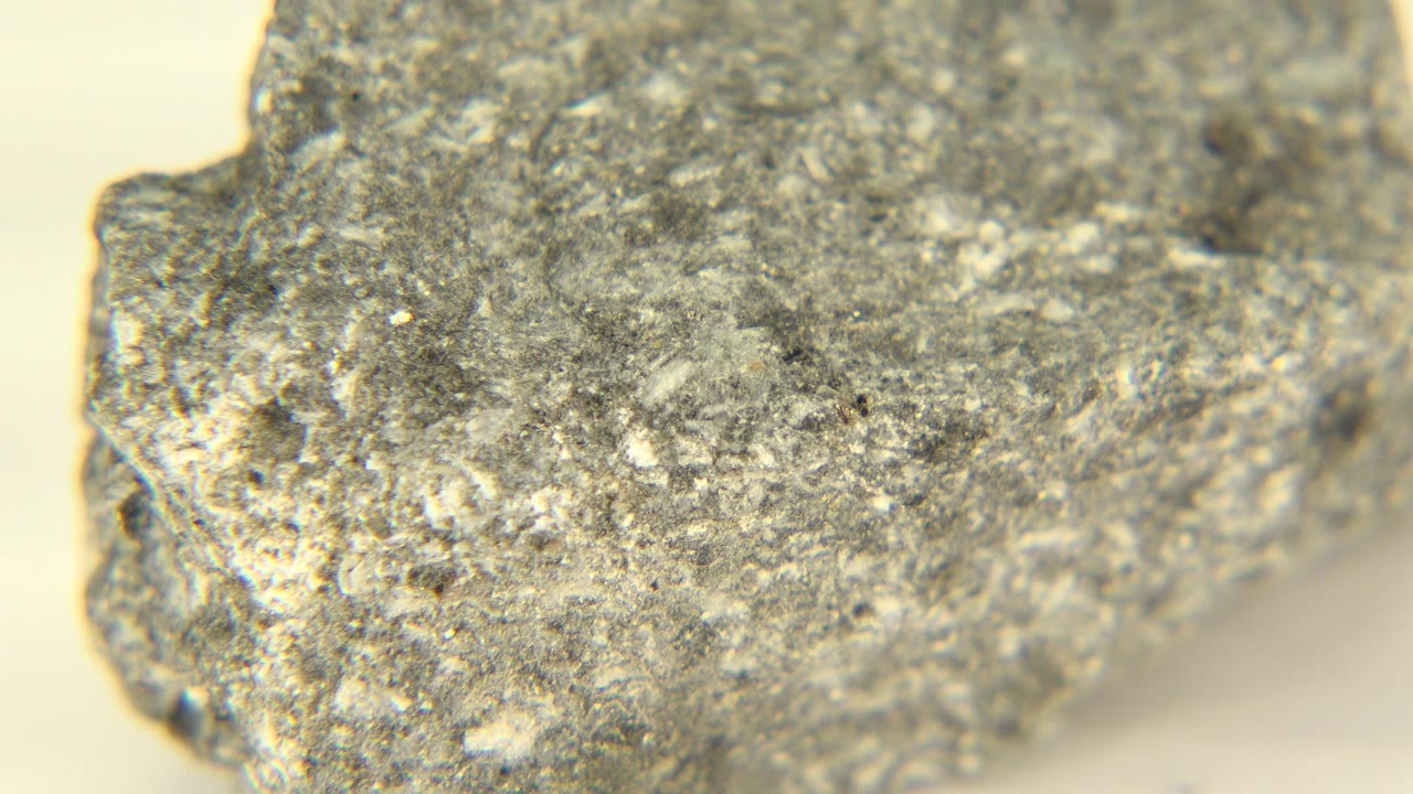 Close view of a rough gray mineral on a pale cream surface in Westminster, Colorado, with soft focus around the edges and no visible people.