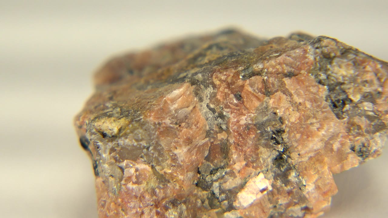 Close-up of a reddish-brown mineral rock with dark patches on a pale tabletop in Westminster, Colorado, with no visible people.