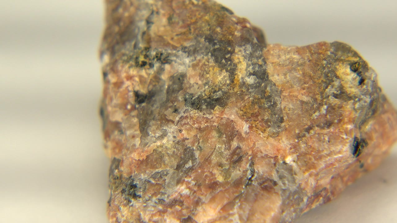 The rock remains in close-up in Westminster, Colorado, turned slightly from the first moment, with rough tan and gray mineral patches and no visible people.