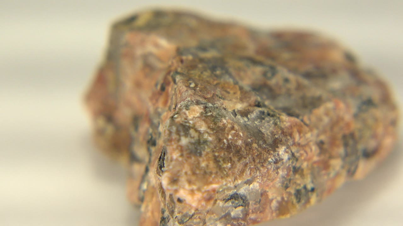 Opening close-up of a pink and grey granite rock in Westminster, Colorado, with dark mineral flecks, soft background blur, and no visible people.