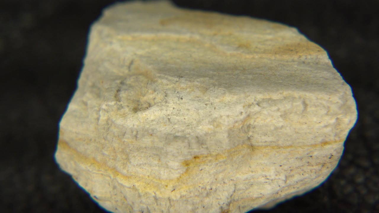 At 0:00, a pale layered rock sits large in frame on a dark textured tabletop in Westminster, Colorado, with no visible people.