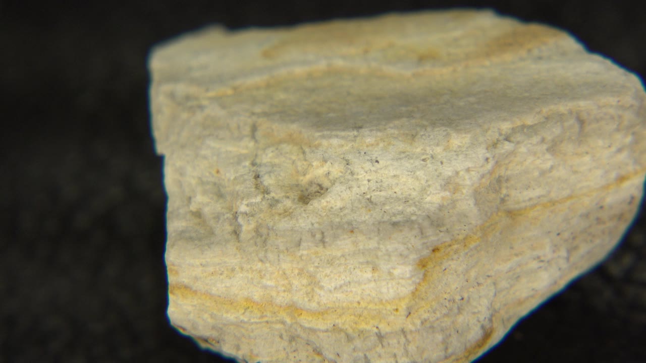 Pale rock showing its right side on a dark tabletop.