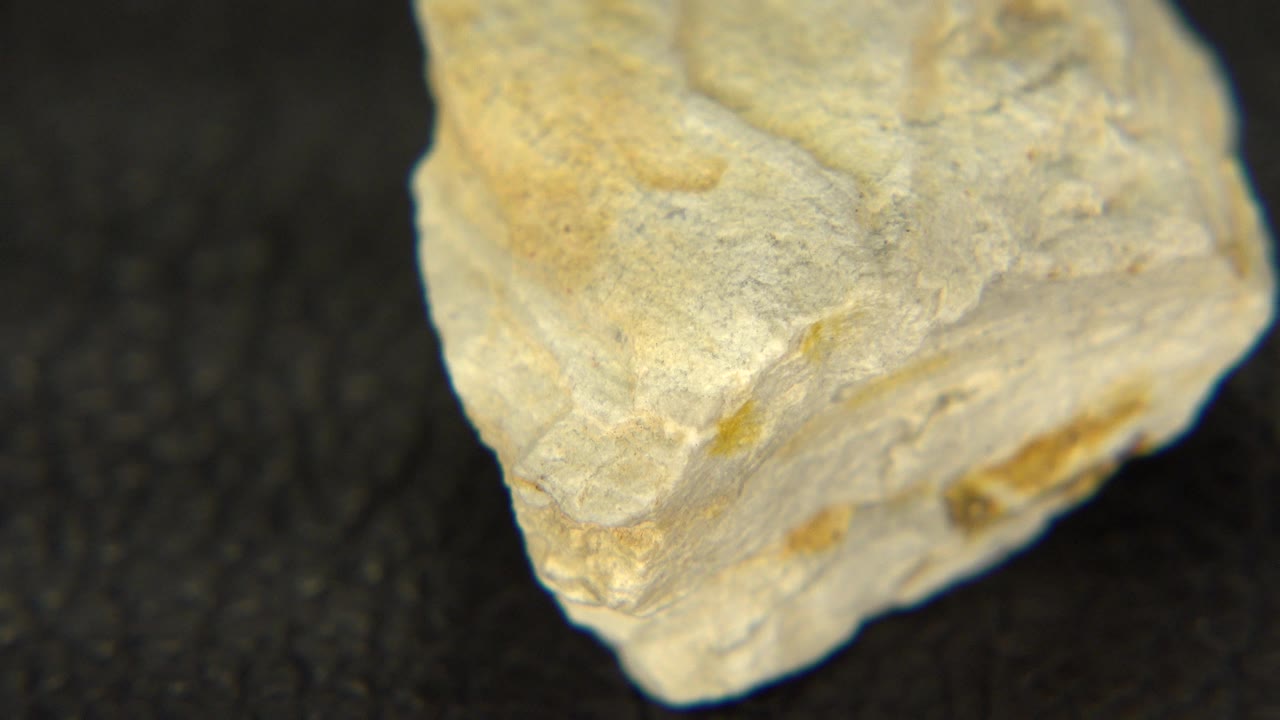 Close view of a pale yellow sandstone quartz specimen on black felt in Westminster, Colorado, with the upper face and chipped front edge visible and no visible people.