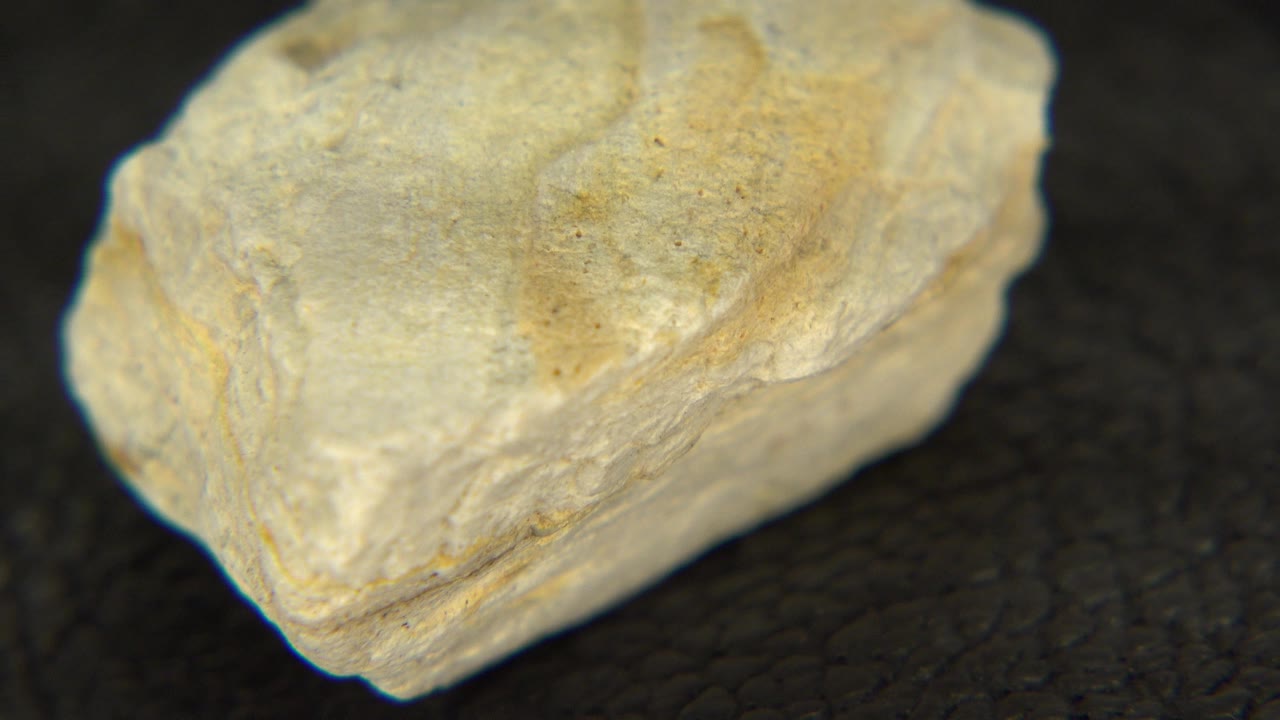 At 0:00, a pale yellow rough stone sits large in close-up on a dark textured surface in Westminster, Colorado footage, with no visible people.