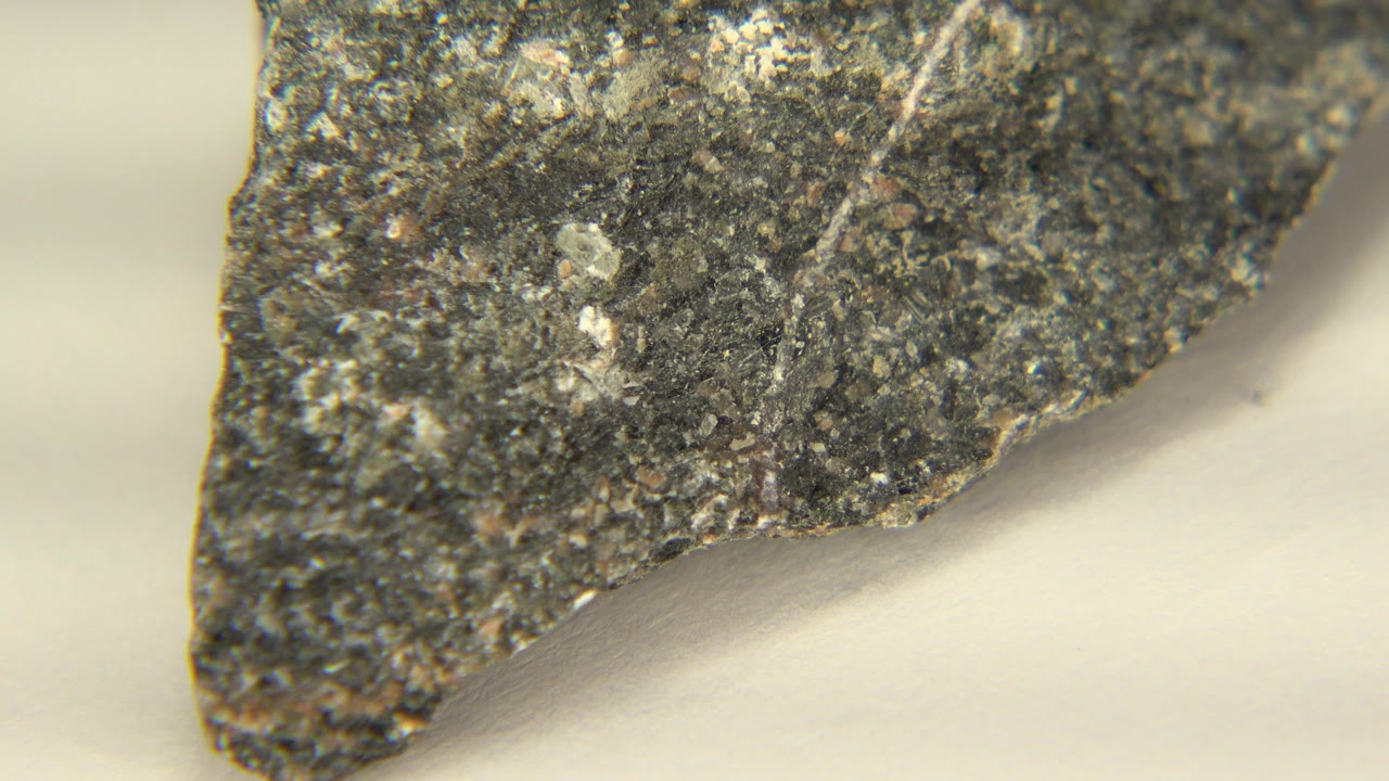 At 0:00, a gray angular rock edge with white sediment flecks fills the left and upper frame in Westminster, Colorado, with no visible people.