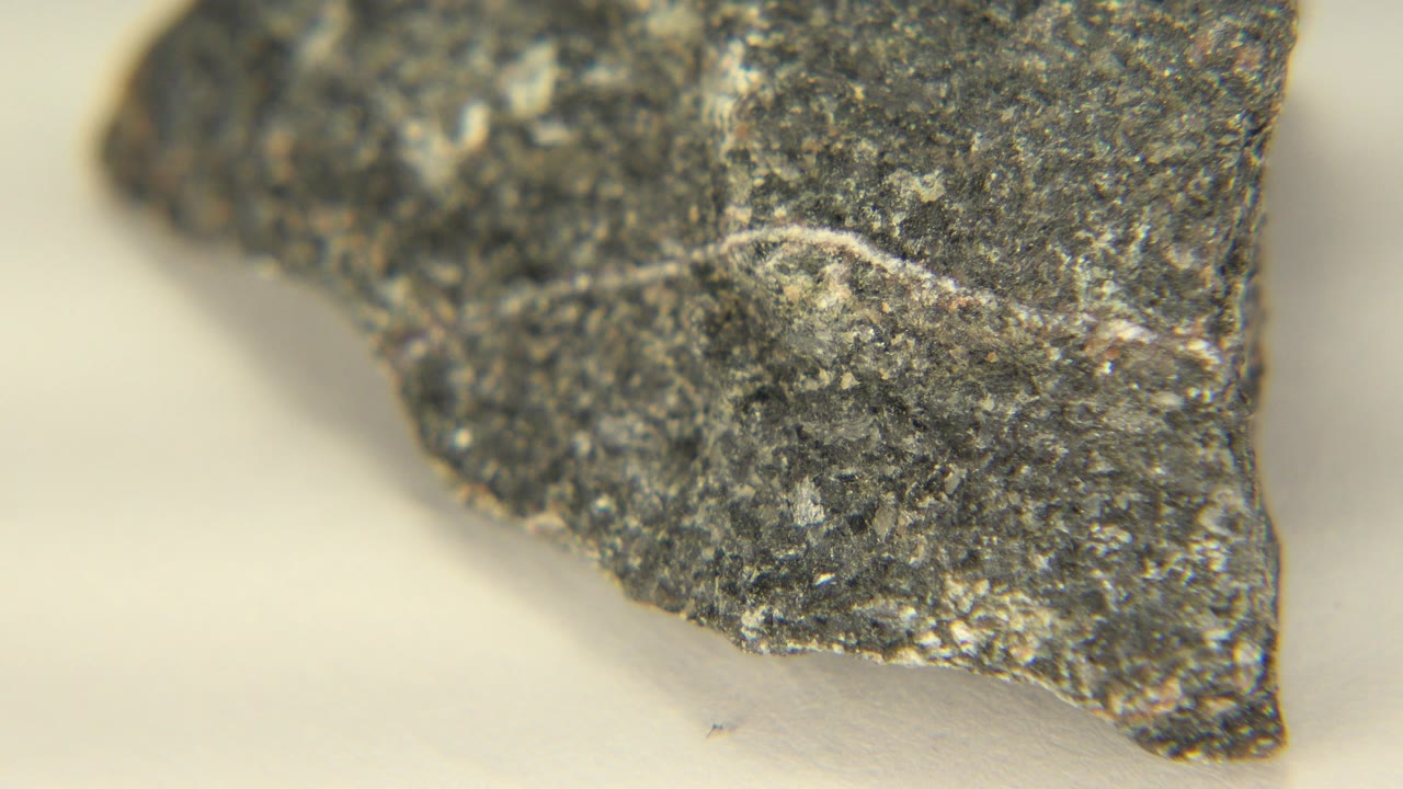 The rock remains in close-up in Westminster, Colorado, with a pale scratch near the center and a small pointed corner over the white floor, no visible people.