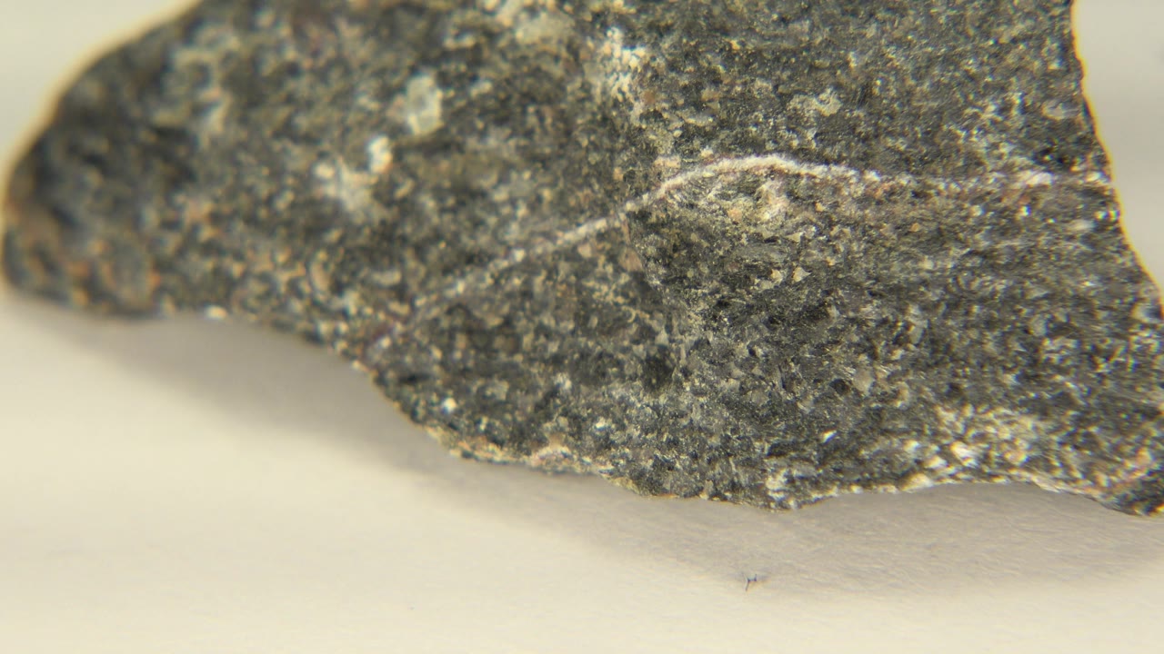 Rotated dark rock edge seen close over a white surface.