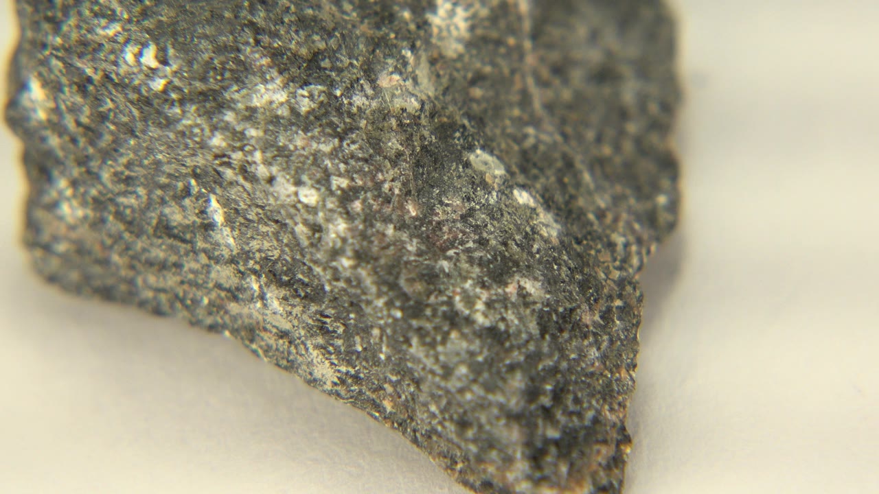 Dark rough rock close-up on a pale table.
