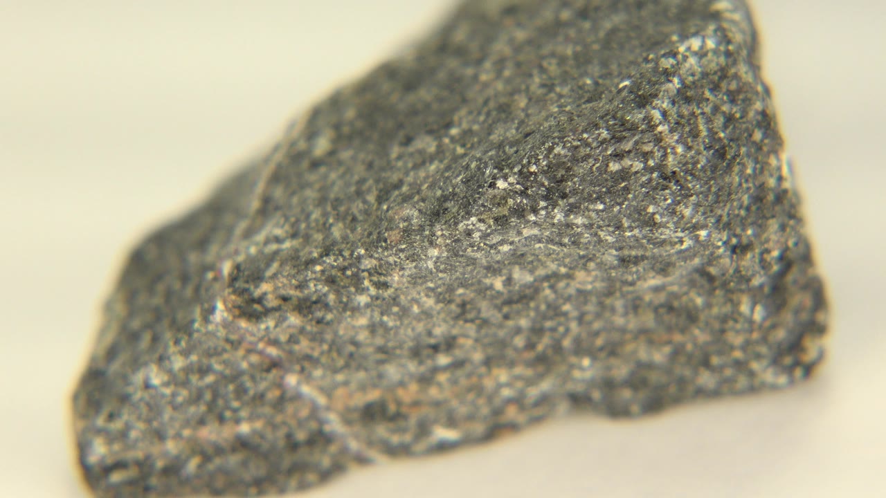 Close-up of the same gray sedimentary rock in Westminster, Colorado, with its upper ridge and speckled fracture surface prominent and no visible people.