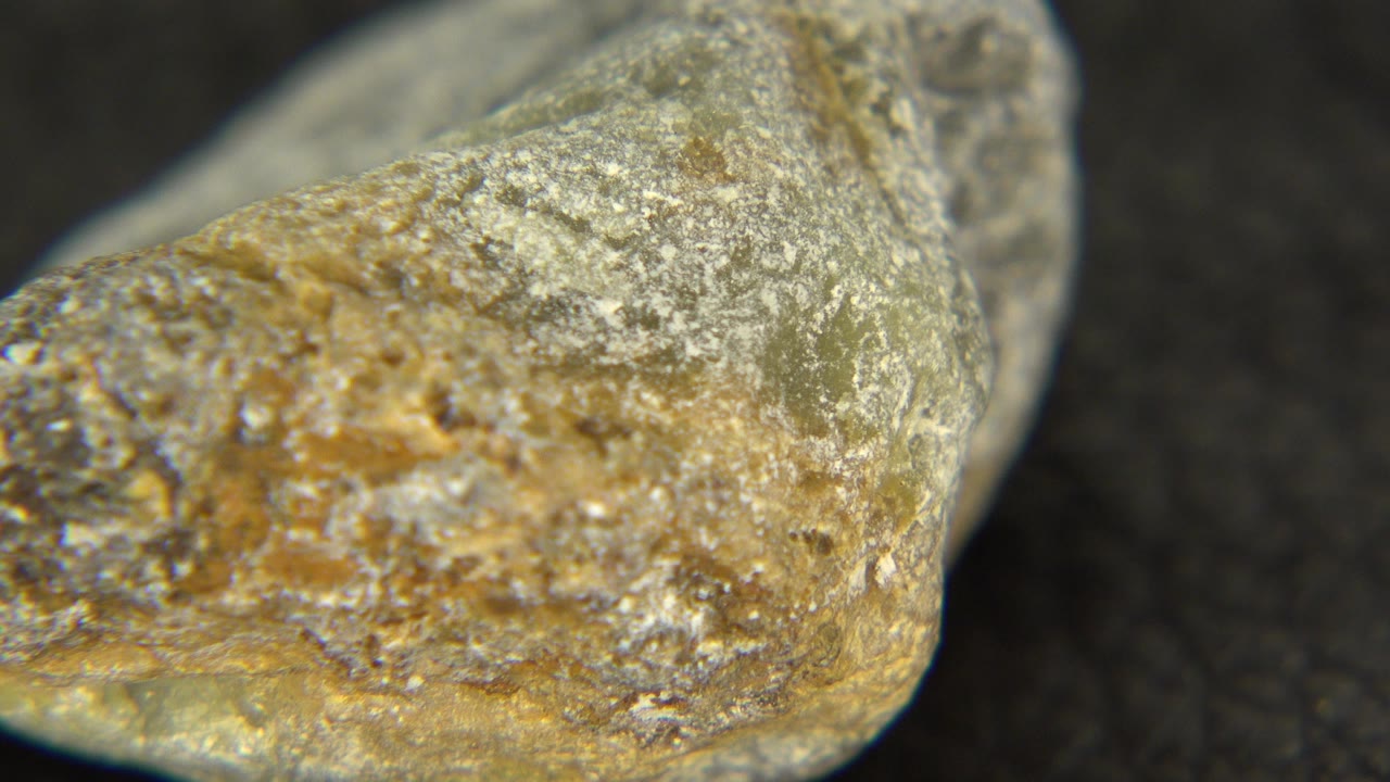 Extreme close-up of a pale gray and amber stone edge in Westminster, Colorado, with granular surface detail and no visible people.