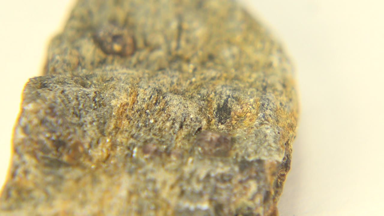 Close view of a carved stone end with uneven edges and dark pits.