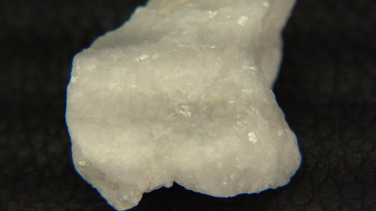 A white crystal rock fills the upper left of the frame on black felt in Westminster, Colorado, with no visible people.