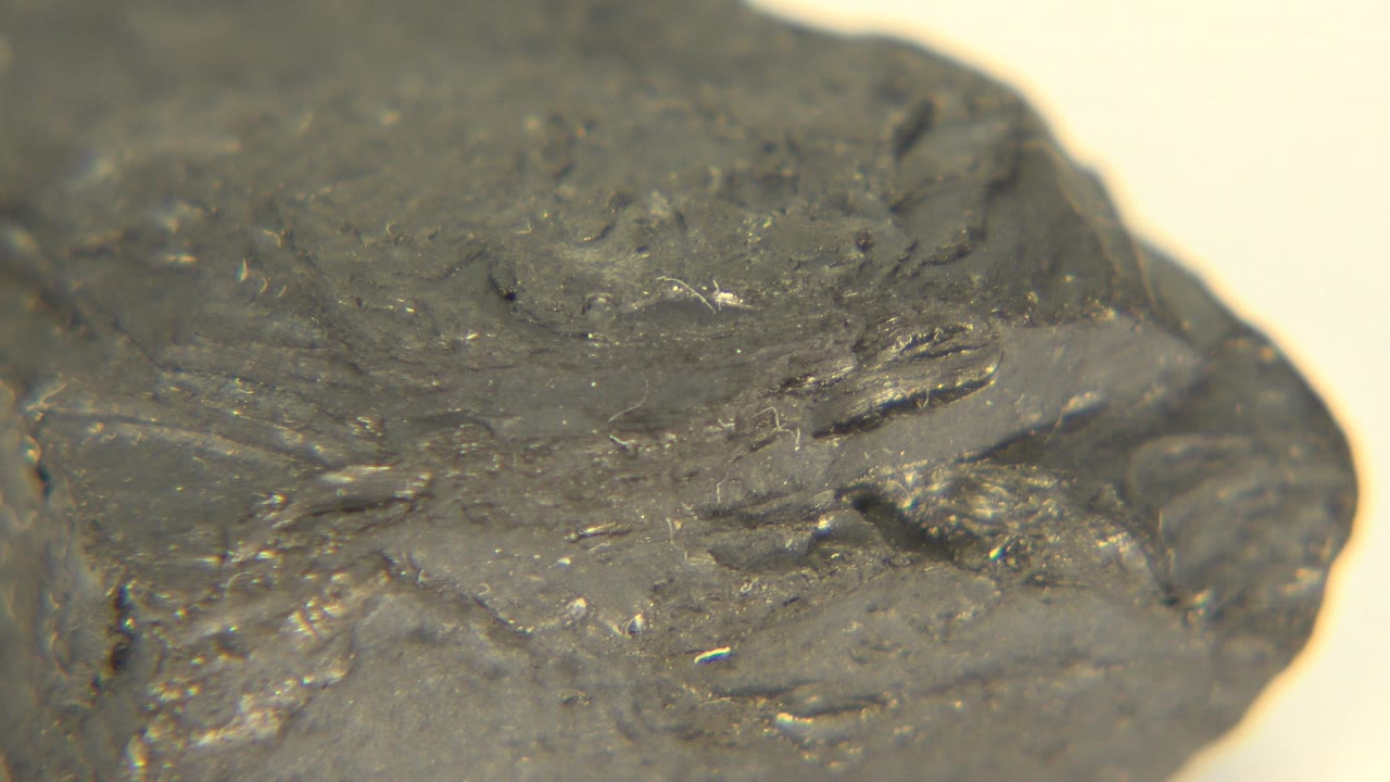The grey rock remains close to camera in Westminster, Colorado footage, with a flatter top area visible and tiny glints on the textured surface, no visible people.
