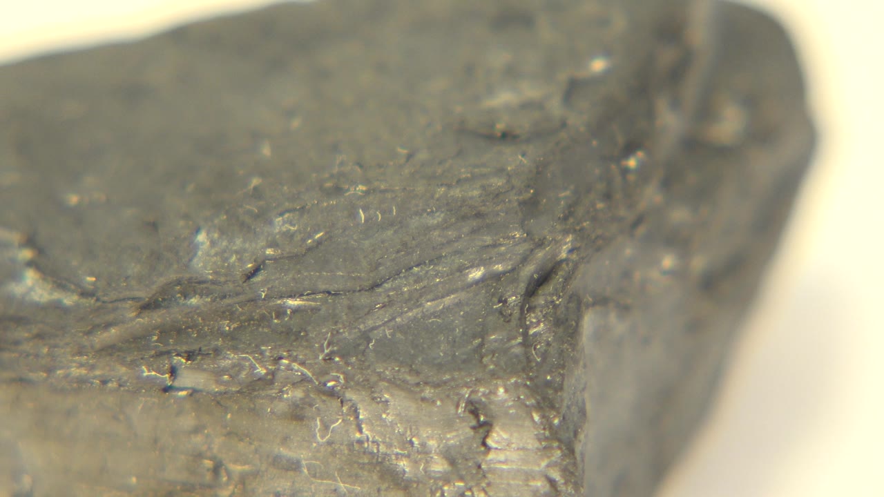 Macro view of the gray rock in Westminster, Colorado, with scratched surface texture and a blurred light tabletop behind it, no visible people.