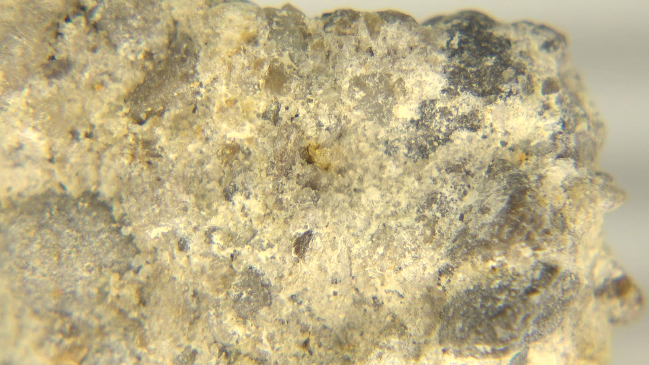 At 0:01, the pitted face of the yellow-gray rock remains close to camera in Westminster, Colorado, showing mottled gray speckles and no visible people.