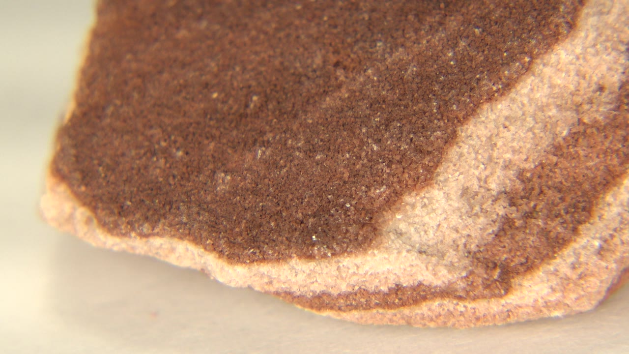 Close-up of a dark brown stone corner with pale layers.