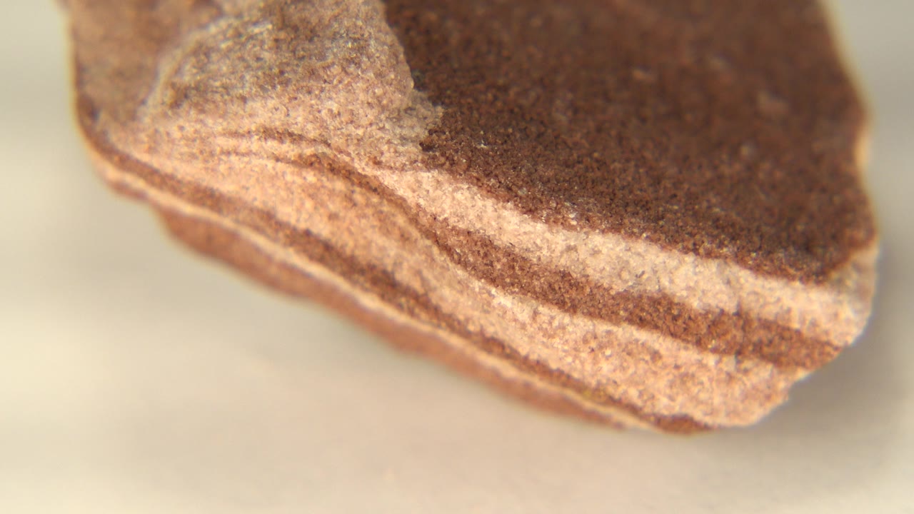 At 0:01, the same banded rock remains in tight close-up in Westminster, Colorado, with the tan stripe running along the lower edge and no visible people.