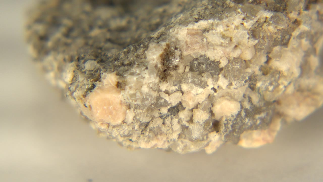 Close-up rock edge with cream grains and dark flecks.