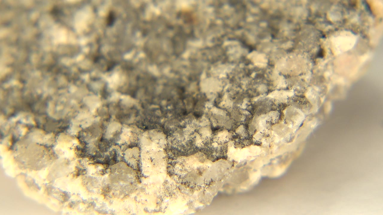 At 0:00, a rough gray and beige rock edge fills the upper frame in Westminster, Colorado, with pale yellow sand on a white floor and no visible people.