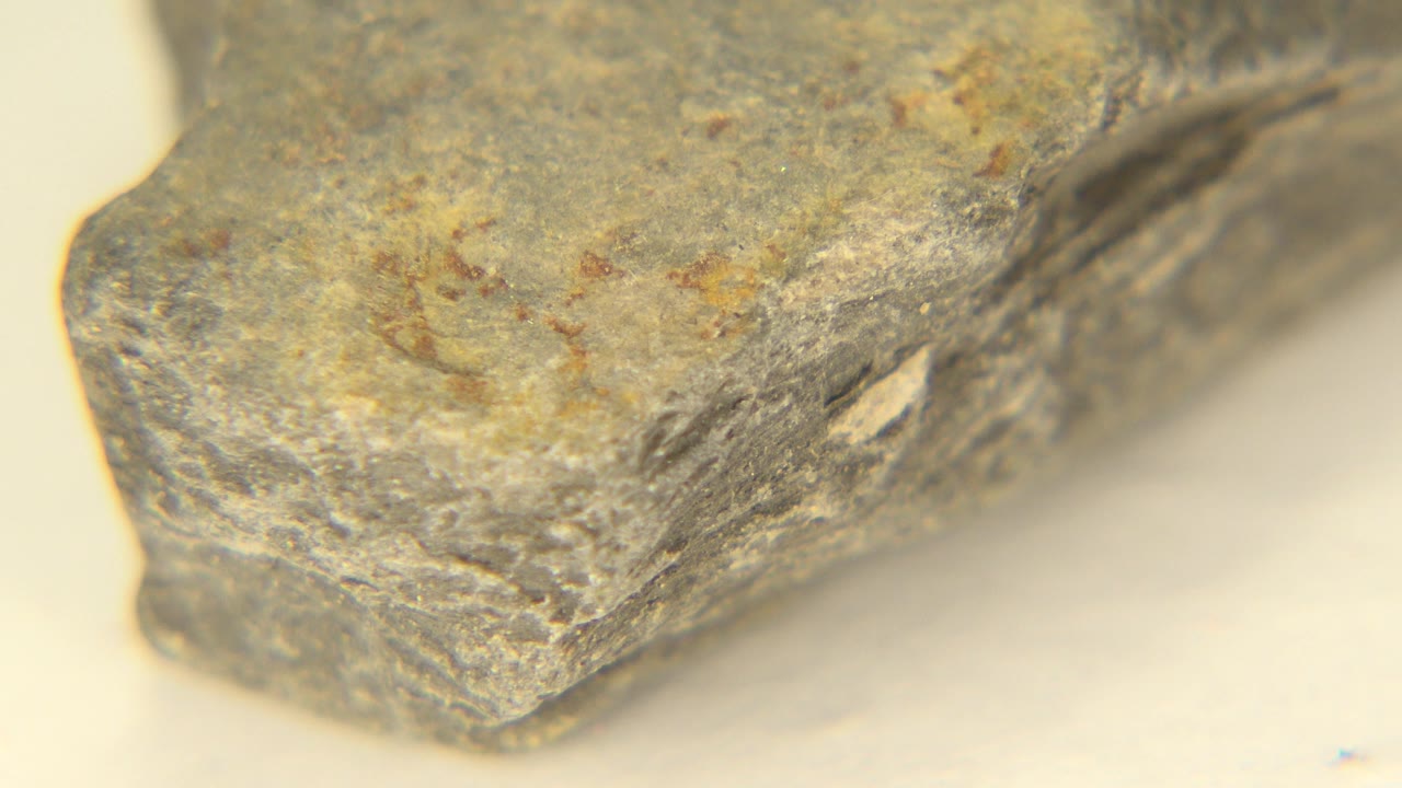 Extreme close-up of a gray rock edge on a pale surface.