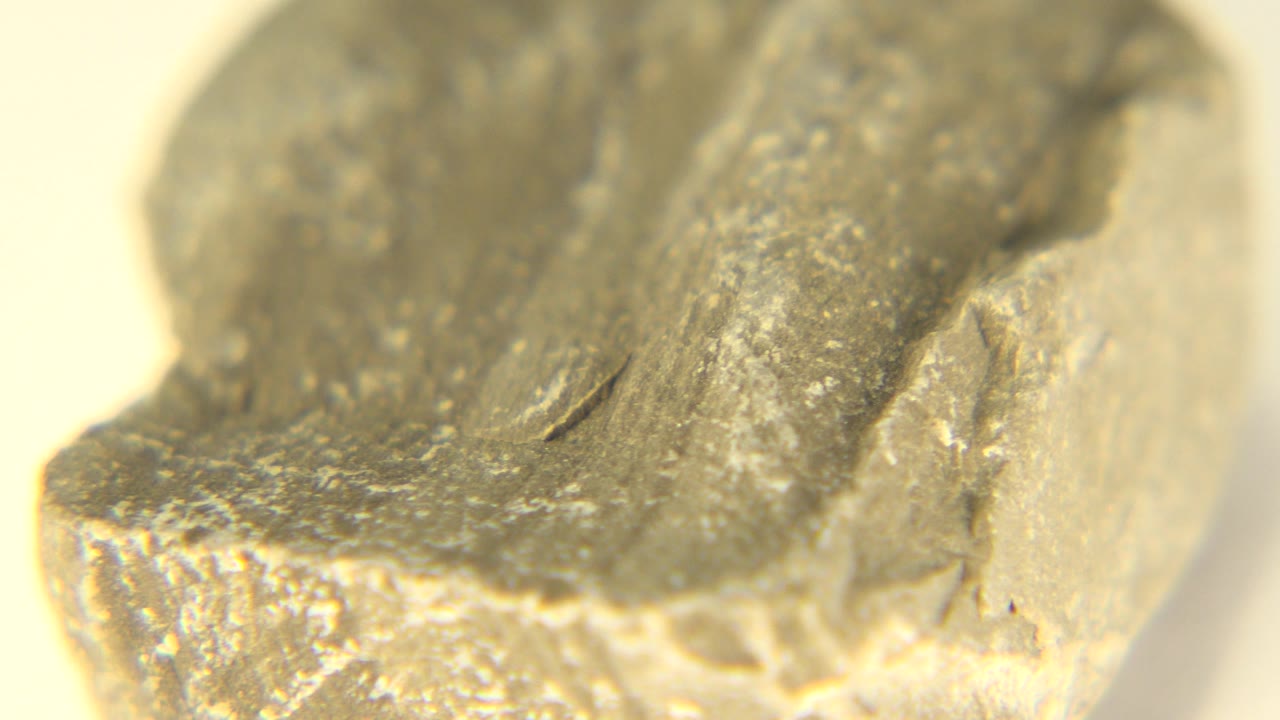Tight close-up of a chipped yellow stone with a darker top surface.