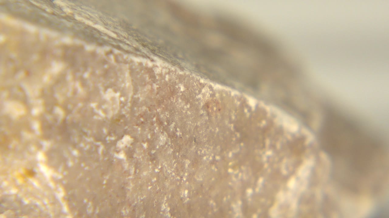 A rough angled section of the Westminster, Colorado rock fills the frame, showing pale specks and a soft out-of-focus upper edge with no visible people.