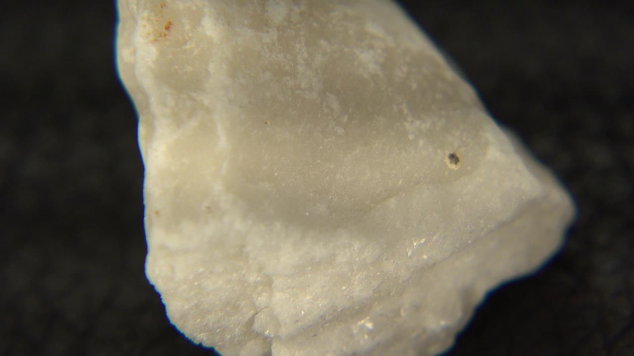 A pale translucent rock or mineral piece fills the first frame against a black background in the Westminster, Colorado 2015 clip, with no visible people.