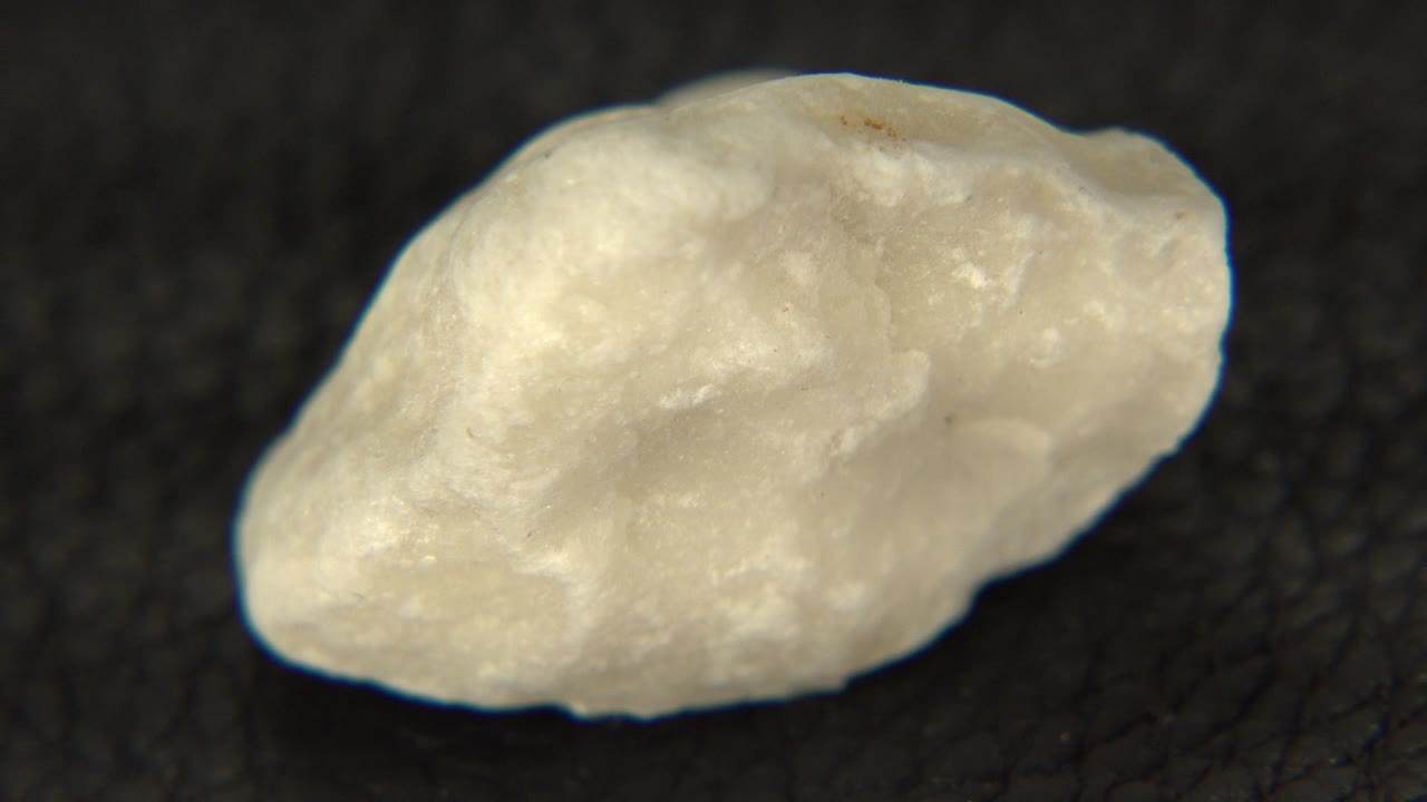 Pale yellow rock on a dark textured tabletop.