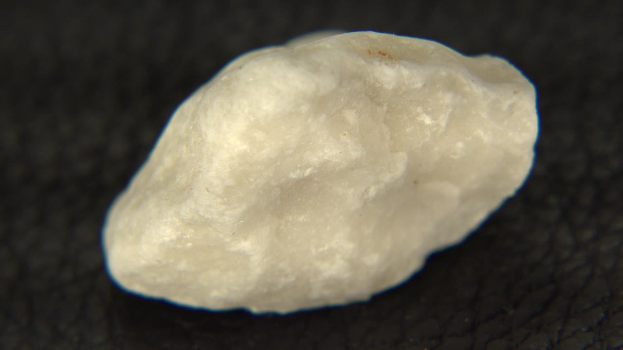 Yellow speckled rock in a tight tabletop close-up, angled slightly differently against the dark surface in Westminster, Colorado, with no visible people.