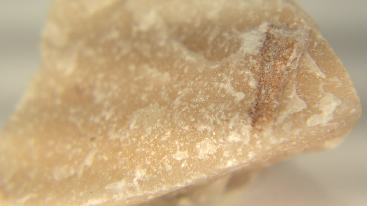At 0:00, a tan yellow sandstone quartz rock fills the frame in Westminster, Colorado, with a rough upper edge, pale flecks, and no visible people.