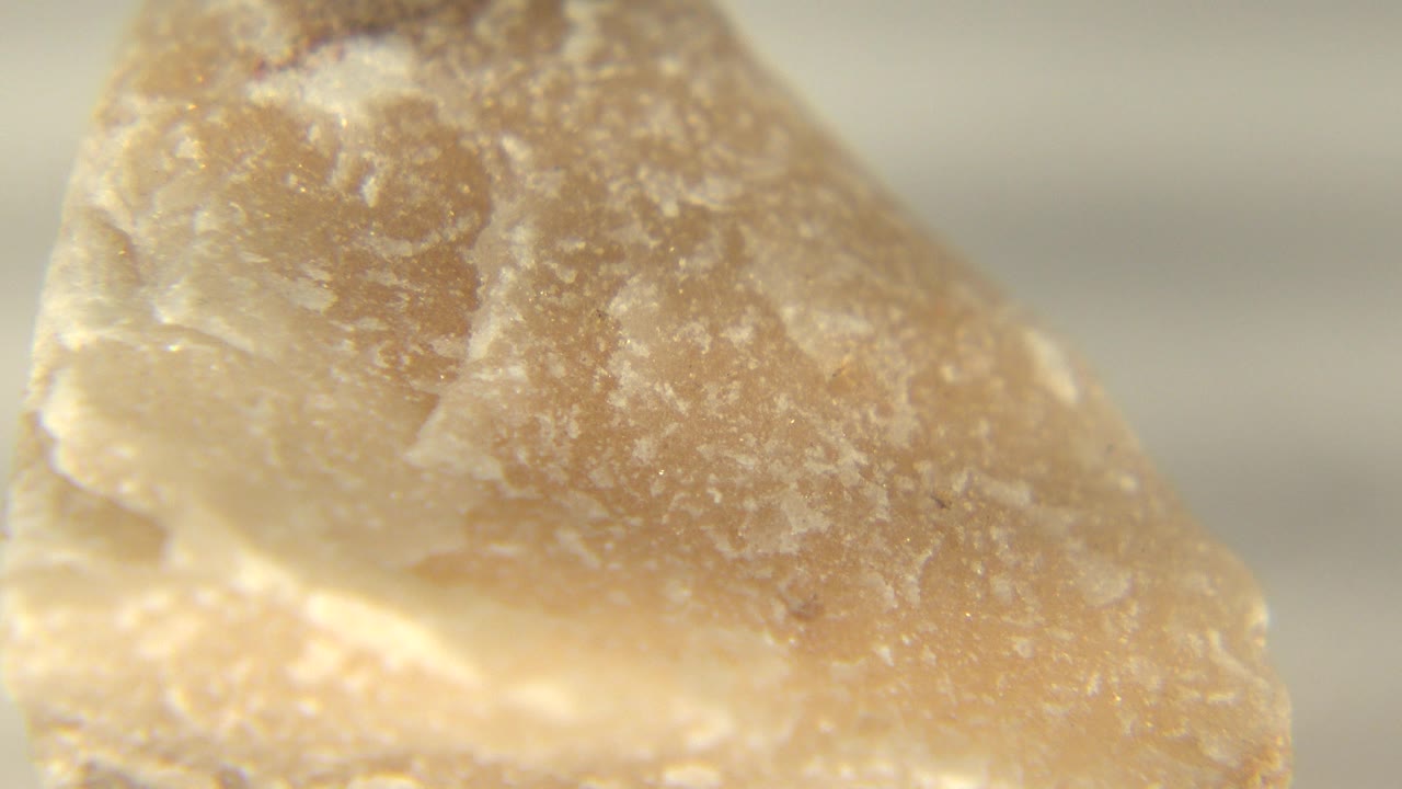 Magnified close-up of a pinkish tan quartz-like stone edge in Westminster, Colorado, with pale crystalline texture and no visible people.