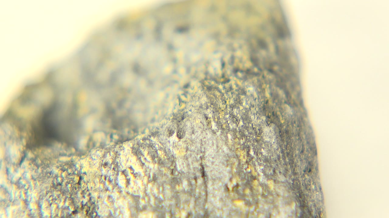 At 0:00, a gray-black rock with yellow speckling fills the frame under bright white light in Westminster, Colorado, with no visible people.