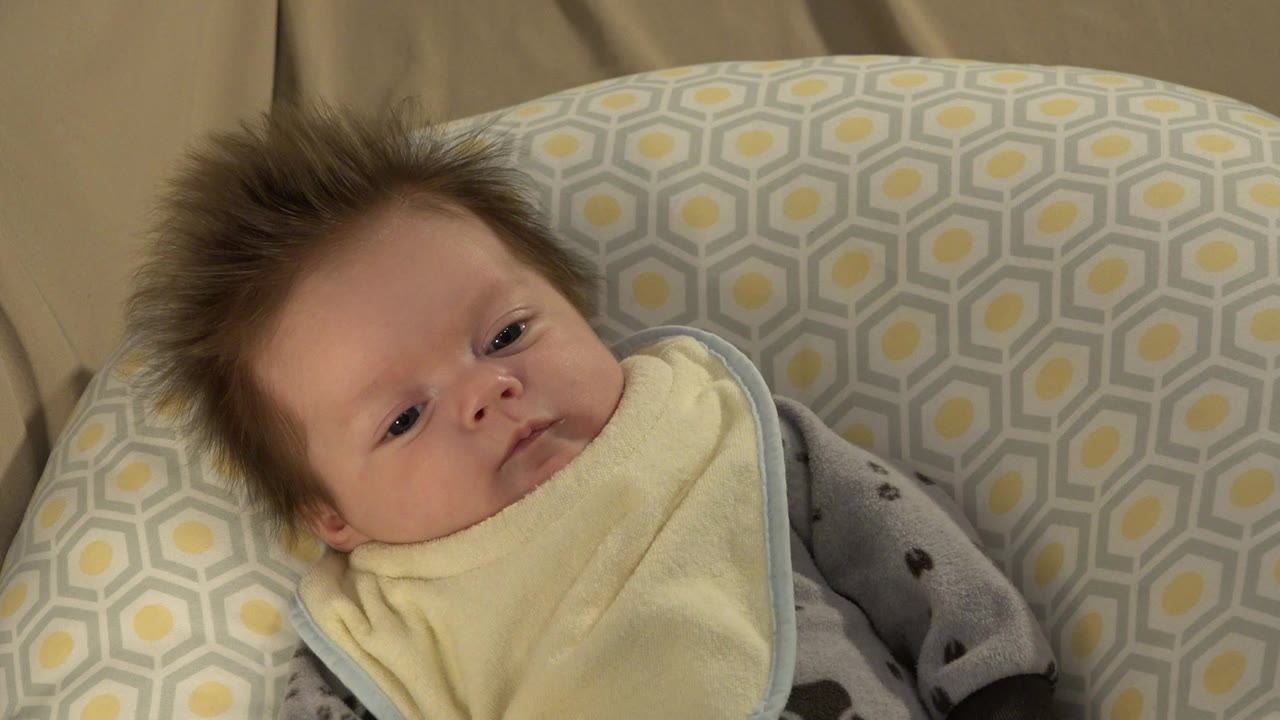 Baby resting in a patterned cushioned chair.