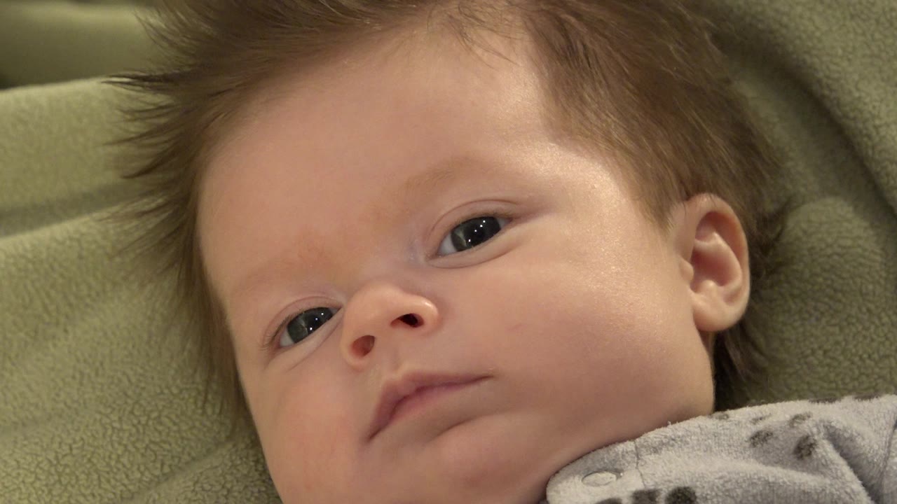 Baby lying on green bedding in a close-up view.