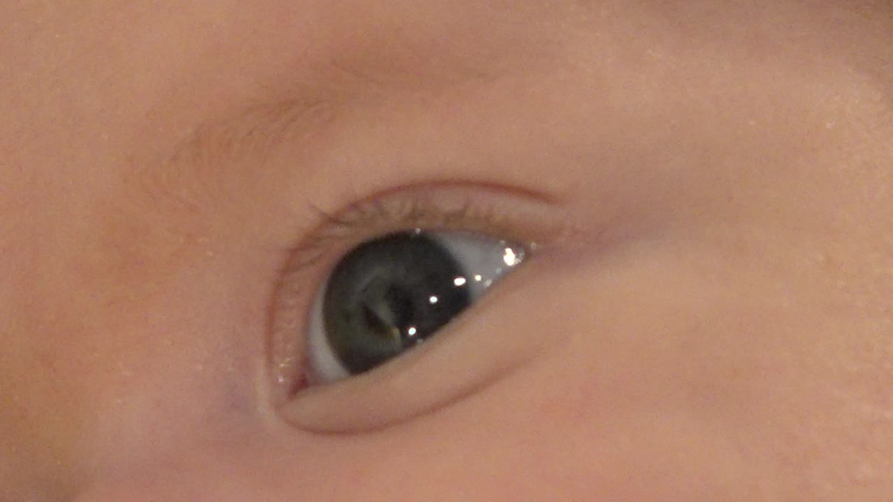Extreme close-up of a baby's glossy eye and eyelid.