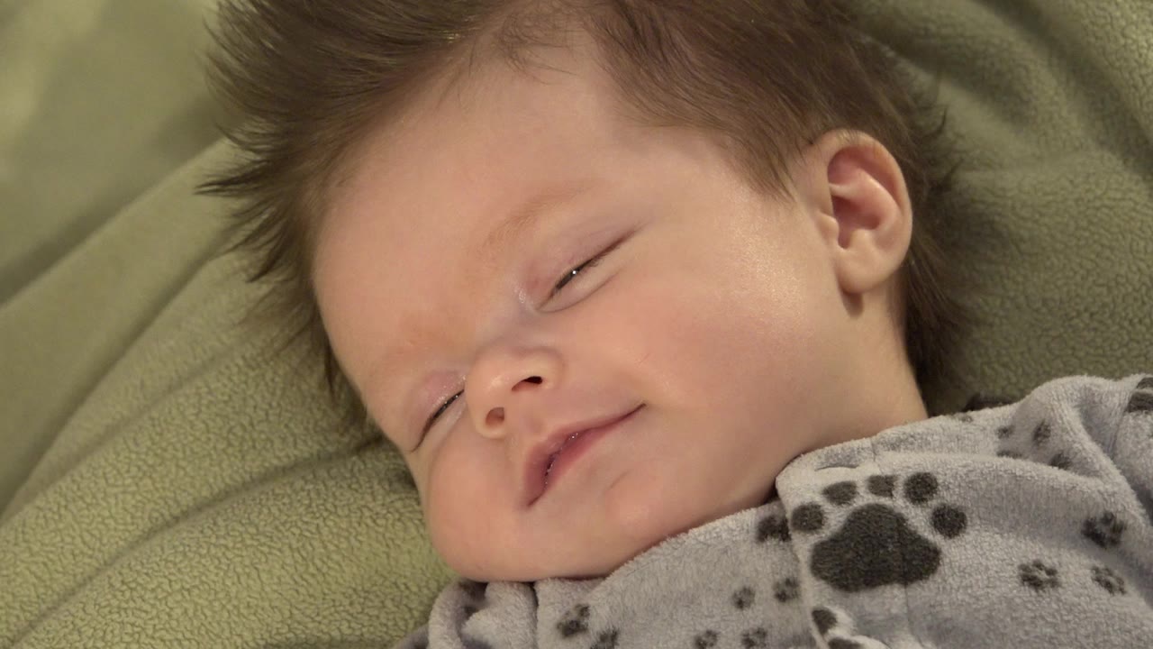 White baby resting on a green blanket with eyes partly open.