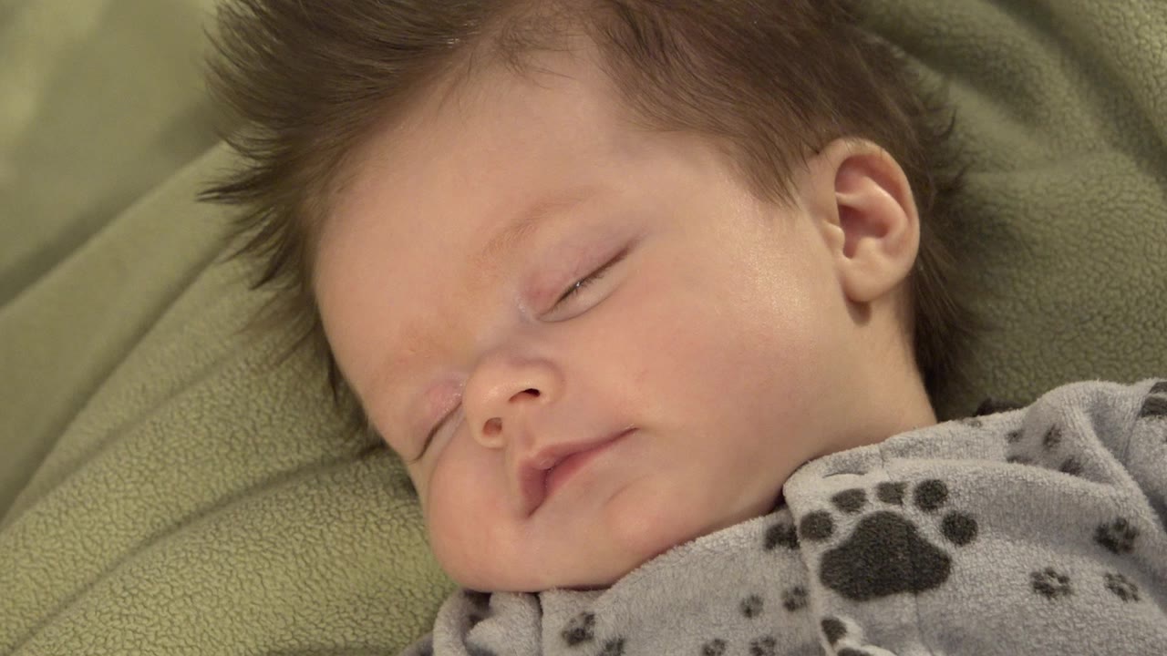 Sleeping baby in close-up on a green blanket.