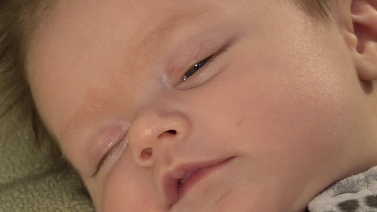 A tight Westminster, Colorado frame shows the infant's cheek, nose, partly open eye, and slightly parted lips under warm indoor light.
