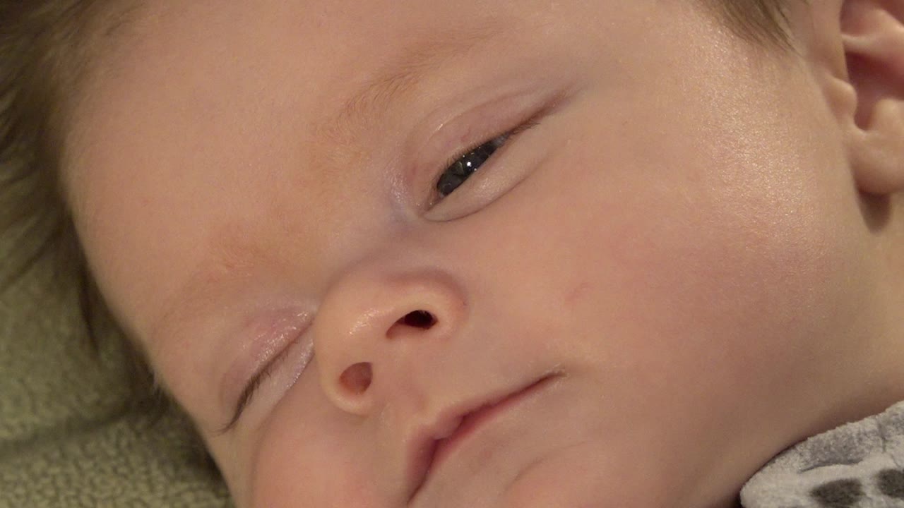 Close-up of a sleeping baby's face on green fabric.