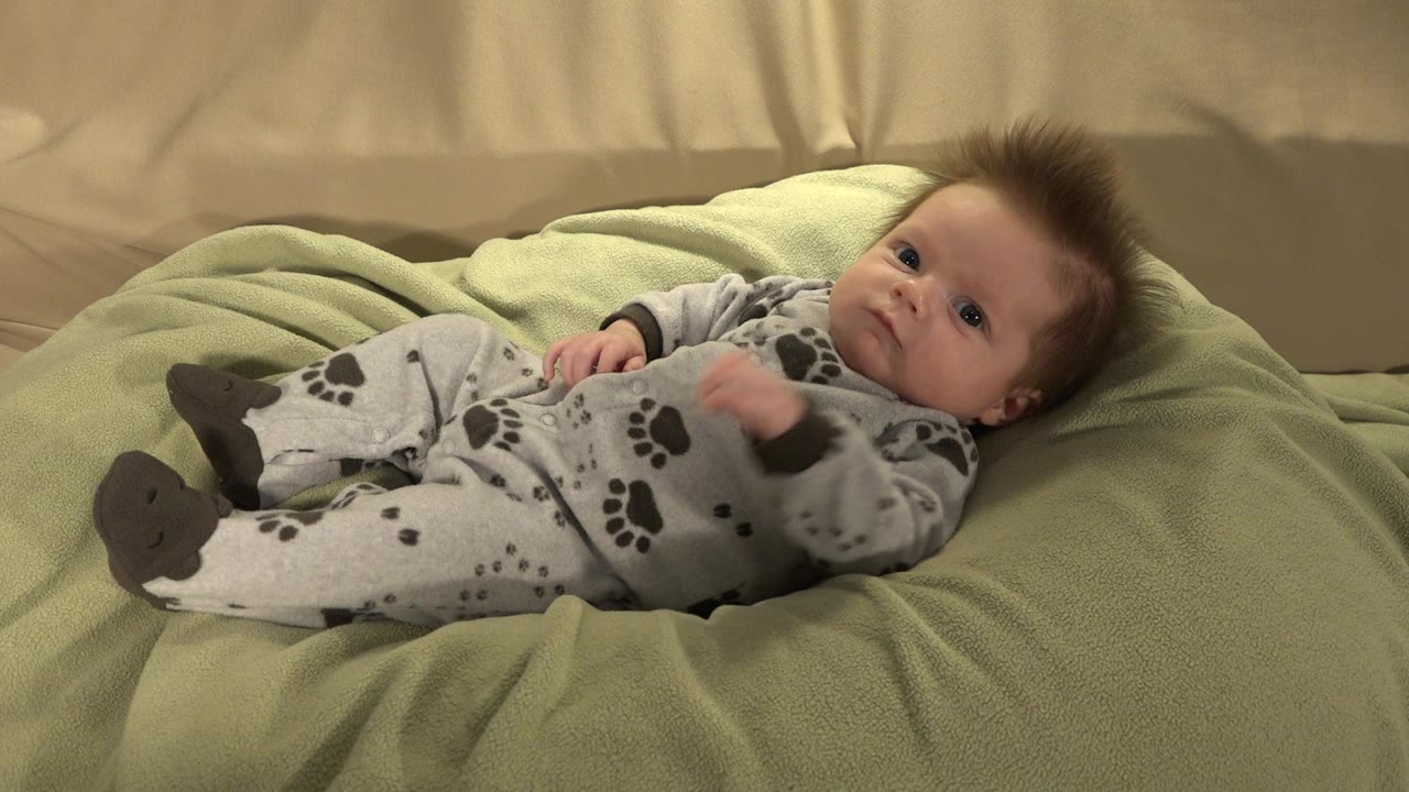 Baby in puppy pajamas lying on a soft green blanket.