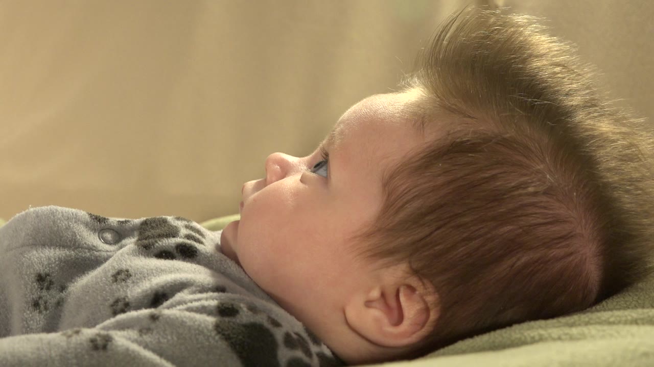 Baby lying in side profile on a green surface.