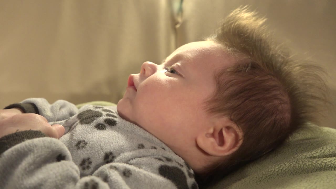 Young child lying on a bed in side profile.