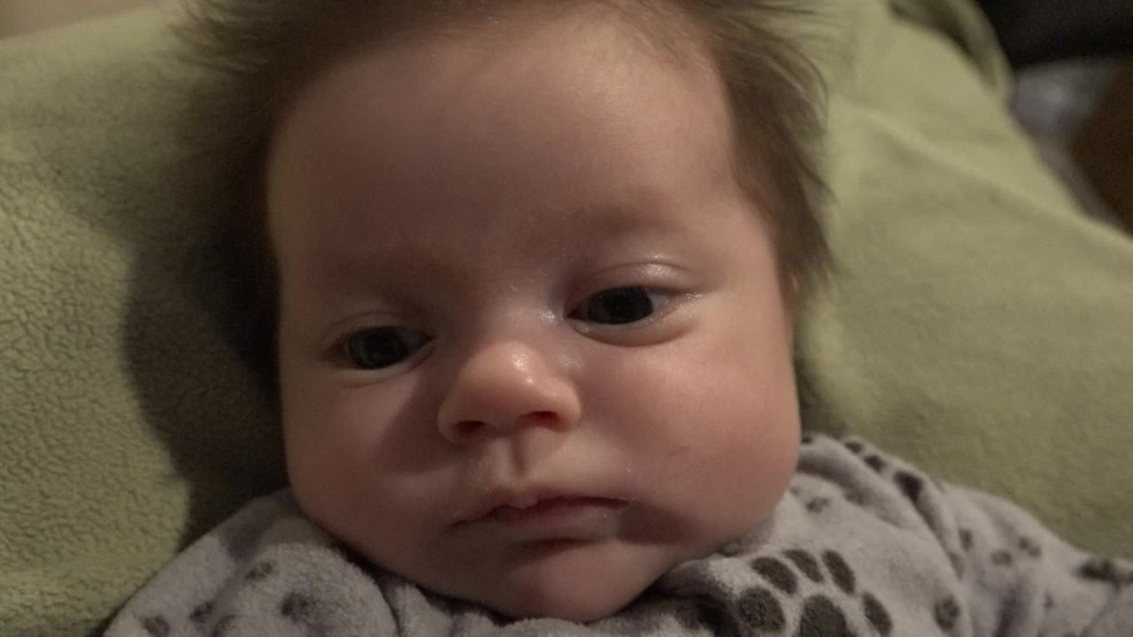 Baby lying on a green blanket in close-up.