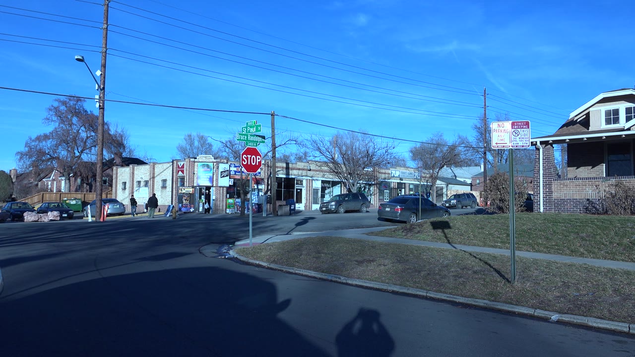 Sunny Denver road corner with stop sign, cars, buildings, and utility wires.