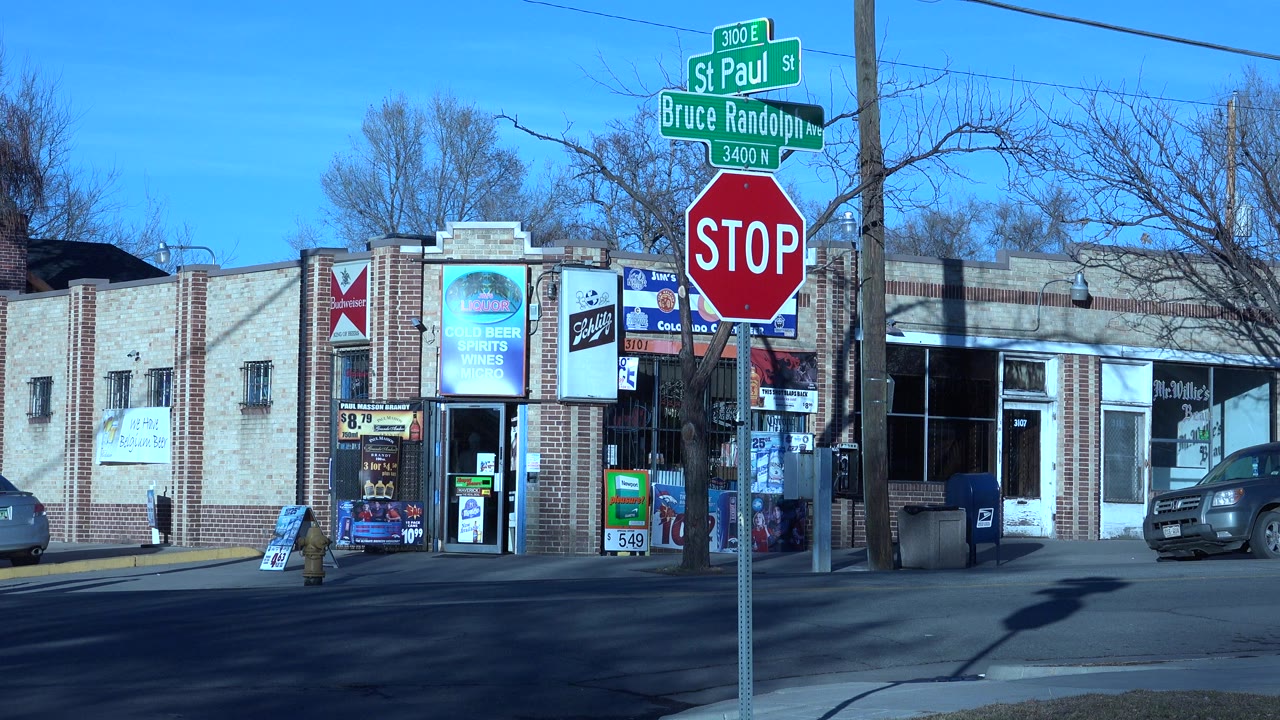 Brick storefronts beside a Denver street with a stop sign in front.
