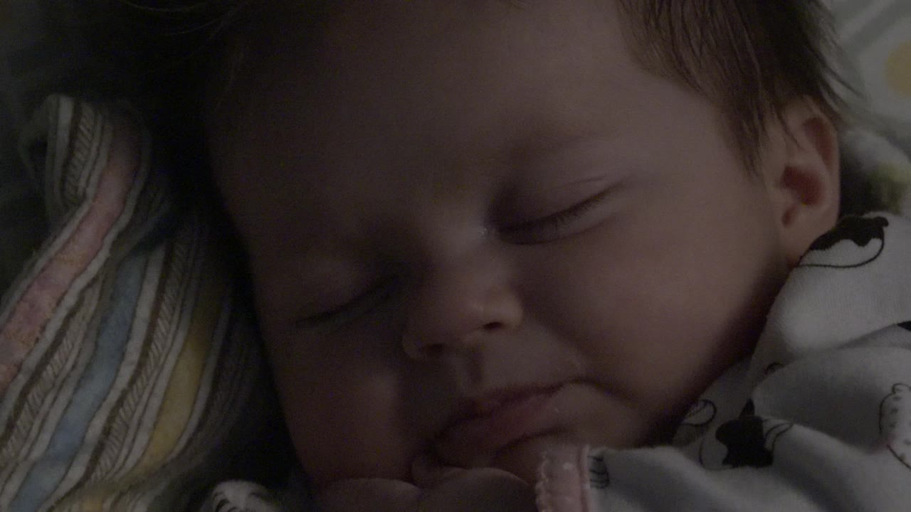 Sleeping baby in close-up on patterned bedding.