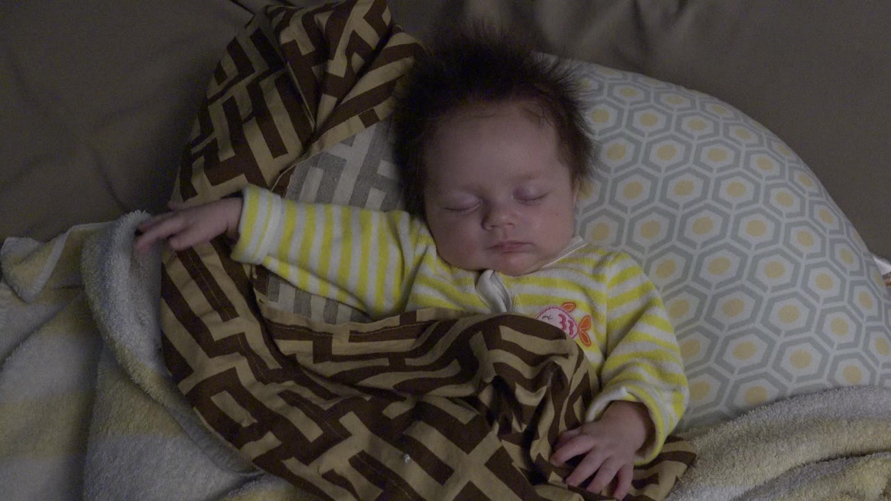 Sleeping child in striped pajamas under a patterned blanket.