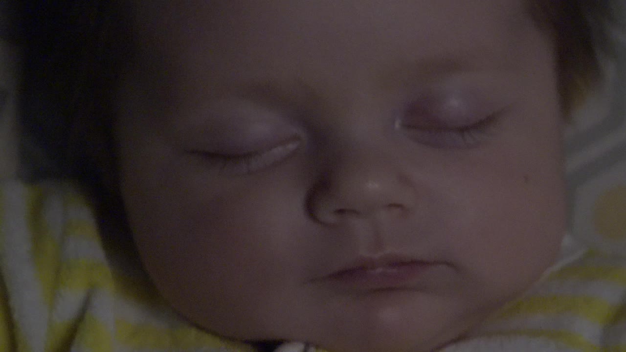 The sleeping infant's face stays centered in the Westminster, Colorado clip, with eyelids closed and the striped garment soft in the lower frame.