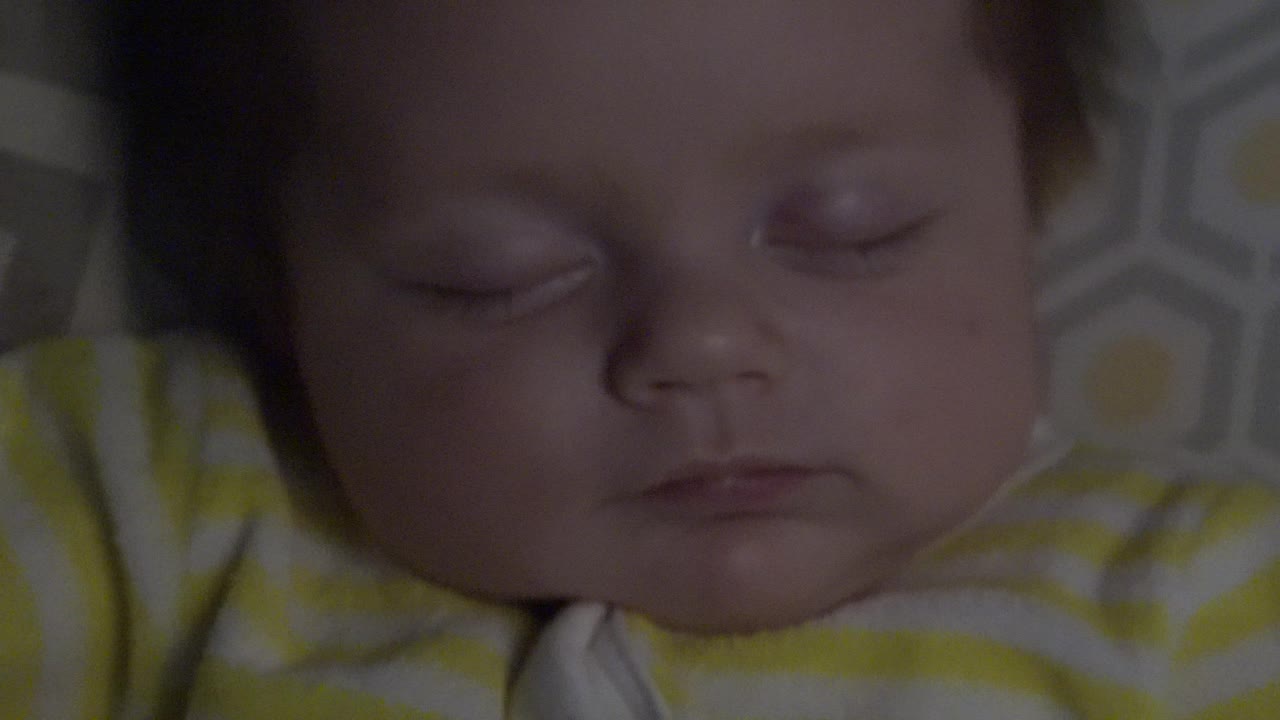 Close view of a sleeping infant's face on patterned bedding.